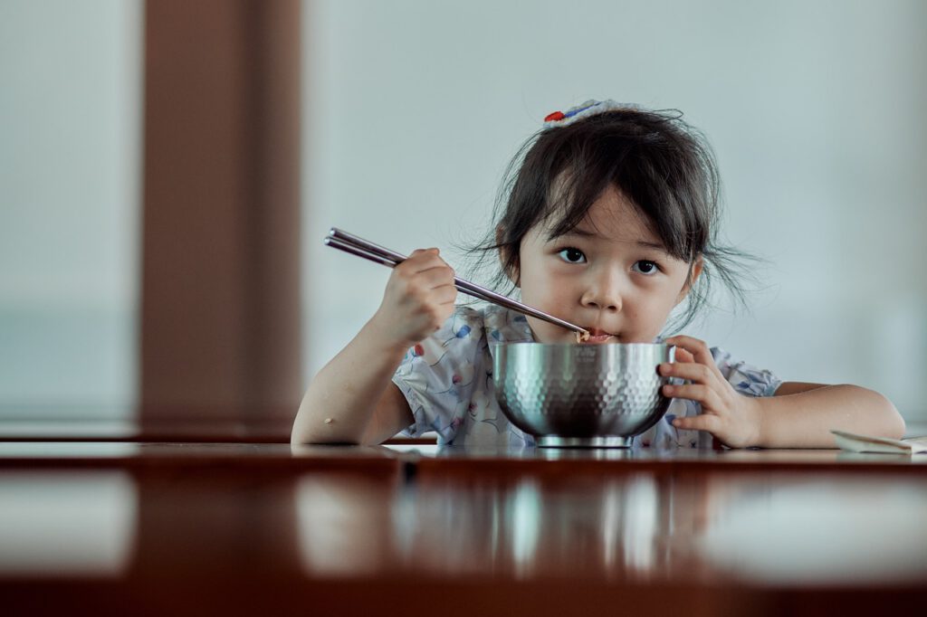 Photo: Child eating with chopsticks